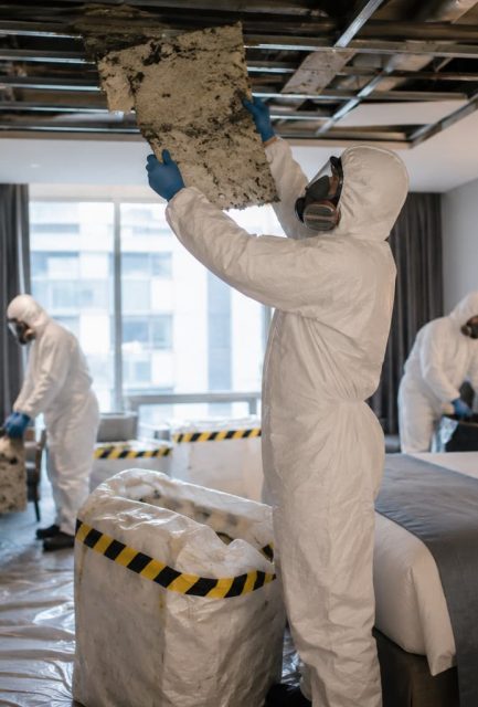 UKATA-trained operatives in full PPE removing asbestos ceiling tiles from a Surrey home with containment sheeting.