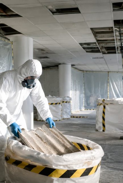 UKATA-trained operatives in full PPE removing asbestos ceiling tiles from a Surrey commercial property with containment.